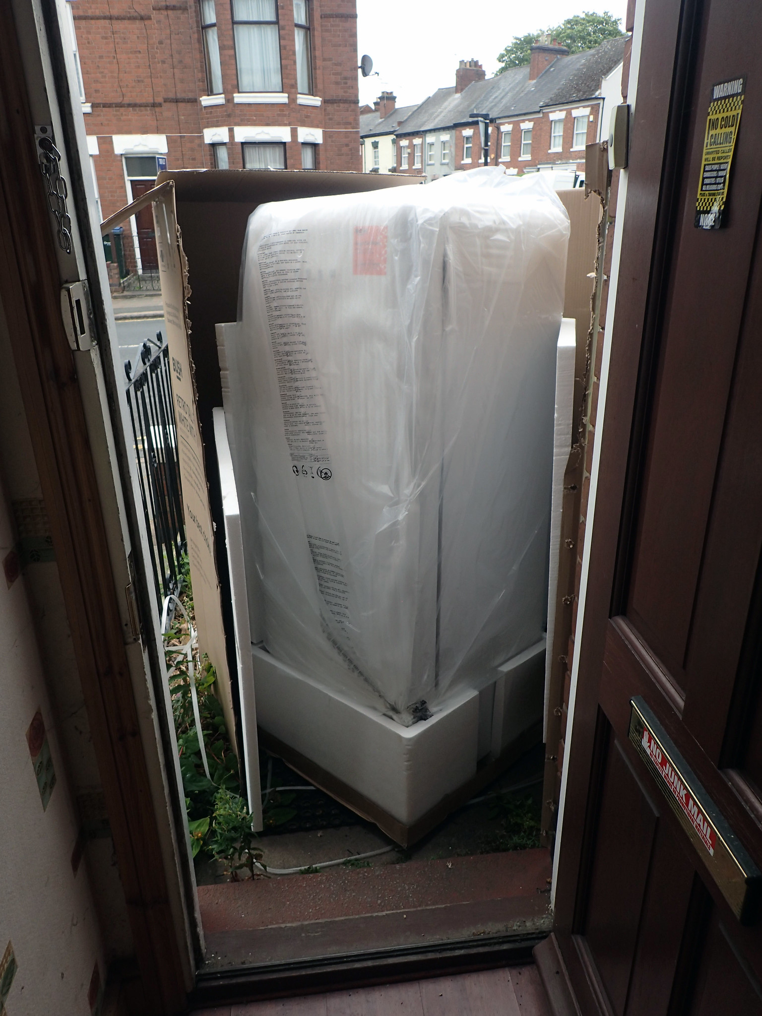 Запакованный холодильник перед входной дверью